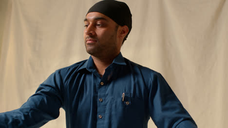 Fotografía-De-Estudio-De-Un-Hombre-Sikh-Doblando-Tela-Para-Un-Turbante-Contra-Un-Fondo-Liso-3